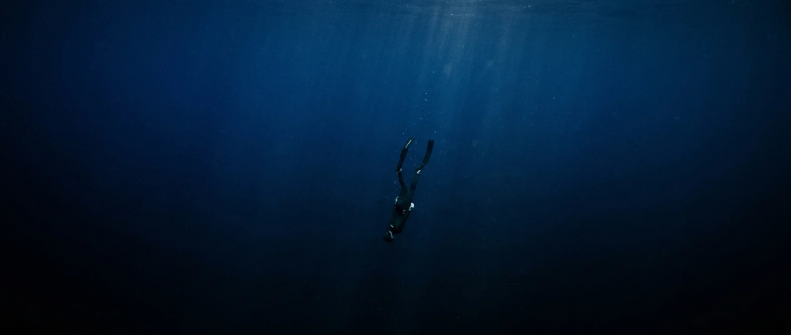 Freediver descending into deep blue ocean without breathing equipment